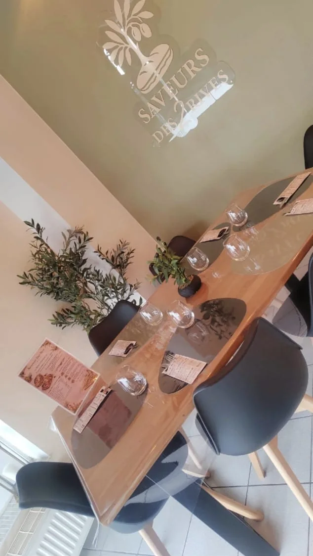 Table dressée dans la salle, sous le logo Saveurs des 2 Rives peint au mur