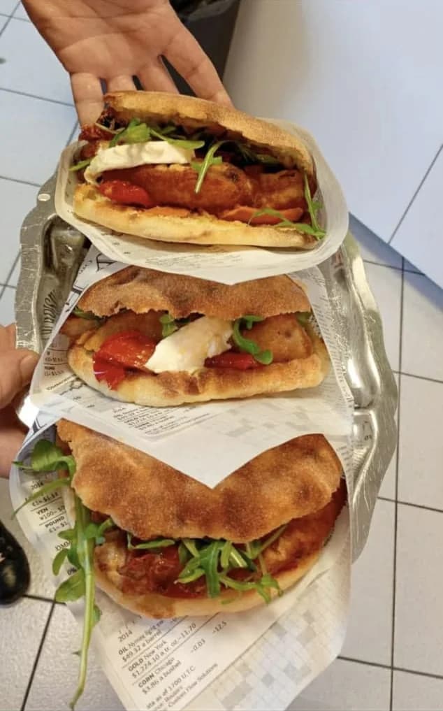 Trois puccias garnies de tomates confites, mozzarella et roquette, servies sur papier